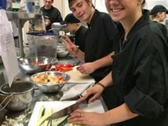 Students in a kitchen smiling and posing