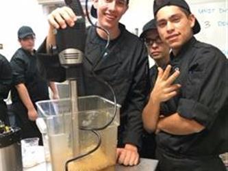 Students using a mixer in a kitchen